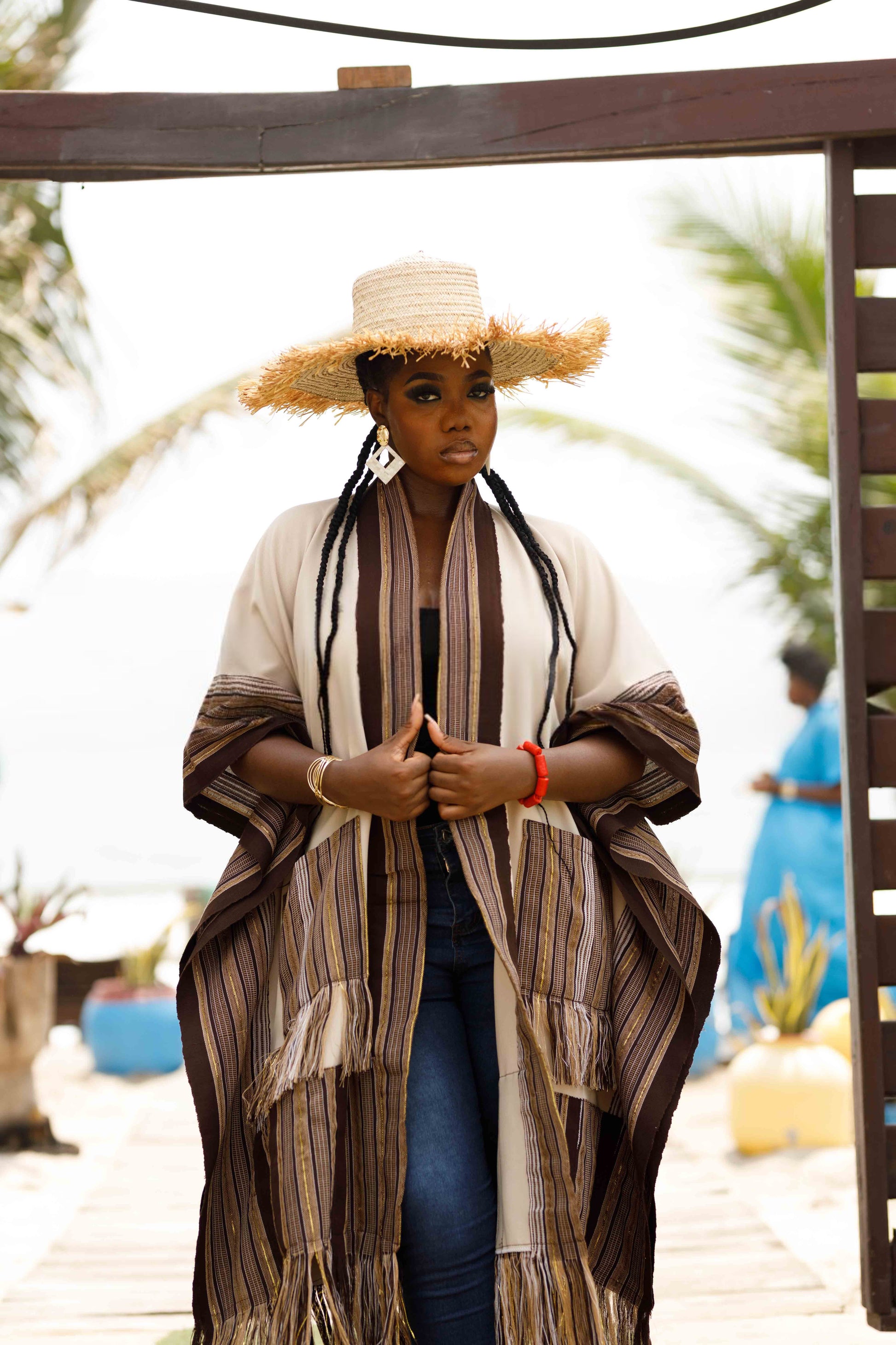 This standout piece is crafted from a thick black cotton crepe base, elevated with boldly striped multicolored woven Asooke panels that trim the silhouette. The edges are intentionally frayed—yet securely finished—creating a striking tassel effect that adds texture and movement to the hem. Complete with matching frayed Asooke patch pockets, this jacket is a cultural classic reimagined for the contemporary wardrobe.